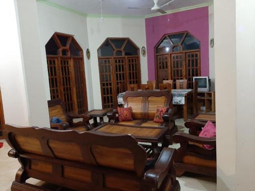 a room with wooden chairs and tables and a tv at The Golden Residence in Kegalle