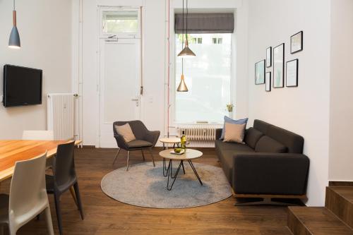 Una sala de estar con un sofá y sillas y una mesa. en BENSIMON apartments Charlottenburg, en Berlín