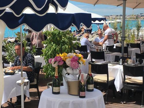 un homme assis à une table avec des fleurs et des bouteilles de vin dans l'établissement Logement climatisé à côté de Negresco et bord de mer, à Nice