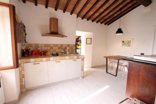 a kitchen with white cabinets and a wooden table at La Casa nel Borgo in Monticchiello