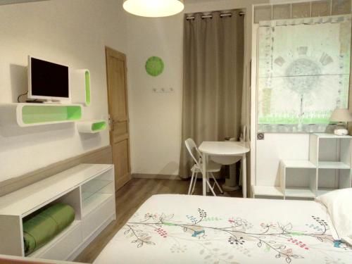 a bedroom with a bed and a desk with a television at Autan des Couleurs in Albi
