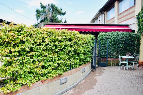 a hedge in front of a building with a table at Residence Il Portico in Casale Monferrato