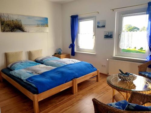 Un dormitorio con una cama con sábanas azules y una mesa. en Villa Wiese en Katzow