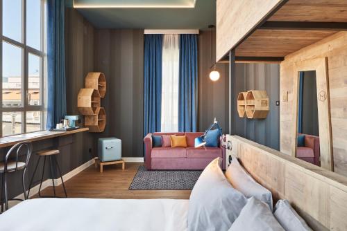 een hotelkamer met een bed en een bank bij The Modernist Hotel in Trieste