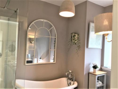 a bathroom with a tub and a mirror at Carnaby Lodge in Dingwall