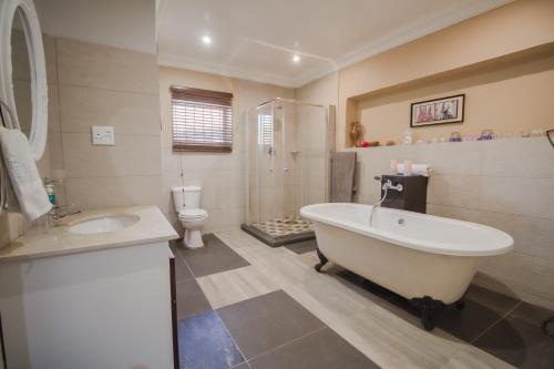 La salle de bains est pourvue d'une baignoire, d'un lavabo et de toilettes. dans l'établissement The Afropolitan, à Johannesbourg