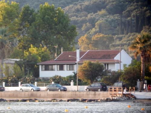 a house with cars parked in front of the water at Eftichia Apartment in Roda