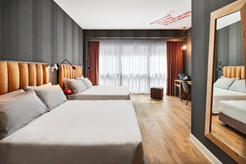 a hotel room with two beds and a mirror at The Modernist Hotel in Trieste
