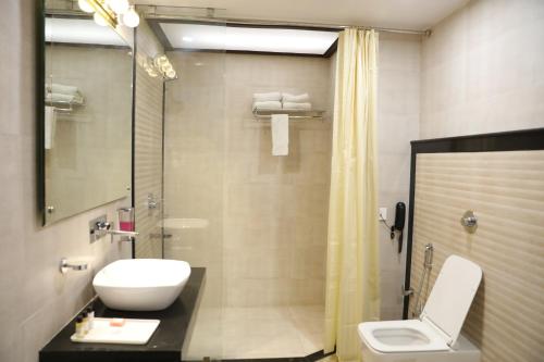 a bathroom with a toilet and a sink and a shower at Hotel Tridev in Varanasi