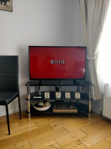 a television sitting on a table with a chair at 2 Bedrooms - 3 Beds - Free Parking - 168 in Stanwell