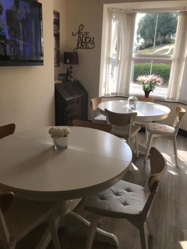 two tables and chairs in a room with a window at Jasmine House in Lutterworth