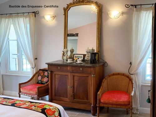 a bedroom with a mirror and a dresser and two chairs at La Bastide des Enquèses in Lorgues