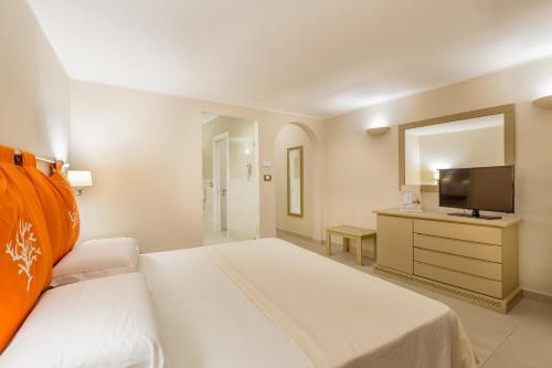 une chambre d'hôtel avec un lit et une télévision dans l'établissement Hotel Cala Lunga, à La Maddalena