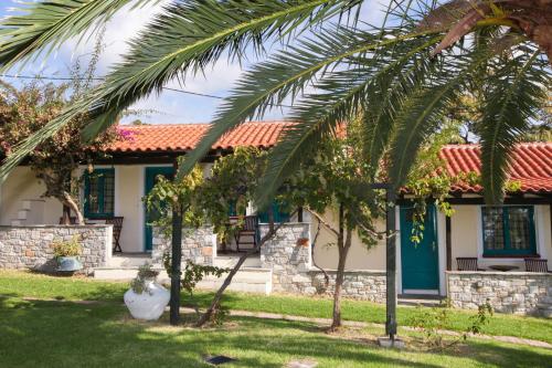 a house with a palm tree in front of it at Angeliki Beach Hotel in Megali Ammos