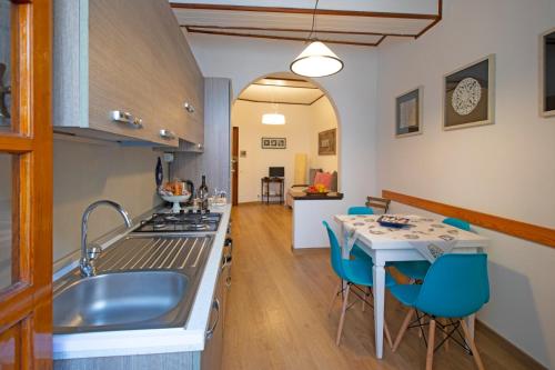 cocina con fregadero y mesa con sillas azules en Ca'la Luna - in centro con terrazza, en Riomaggiore