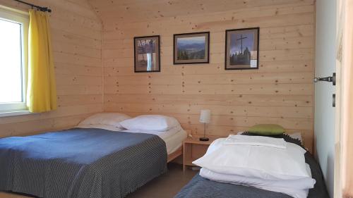 een kamer met 2 bedden in een houten muur bij Podbucznik 3 Leskowiec in Targoszów