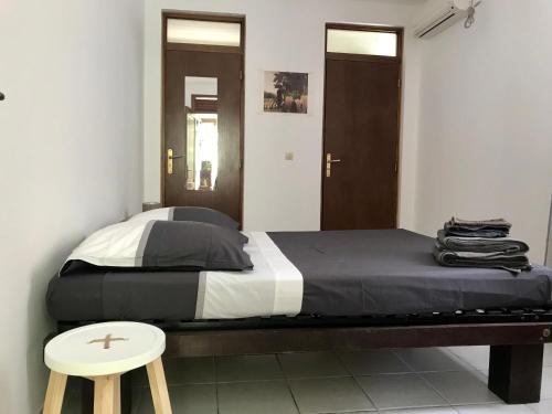 1 dormitorio con 1 cama, 1 taburete y 2 puertas en Villa Figues et Mangos, en Terre-de-Haut