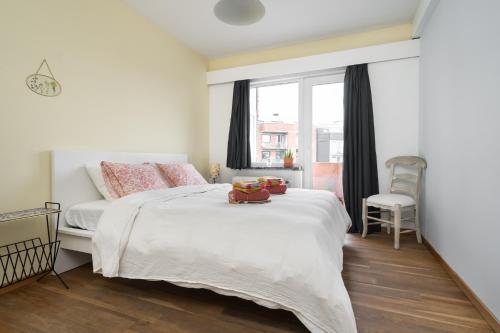 ein Schlafzimmer mit einem weißen Bett und einem Fenster in der Unterkunft Gezellig app in de Belle Époque wijk van Oostende in Ostende
