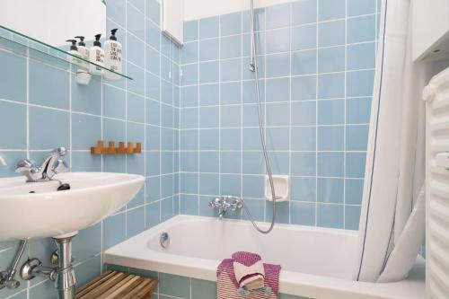 a blue tiled bathroom with a sink and a tub at Gezellig app in de Belle Époque wijk van Oostende in Ostend