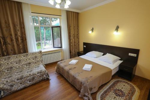 a bedroom with a bed and a couch and a window at Hotel Kavkaz in Arkhyz