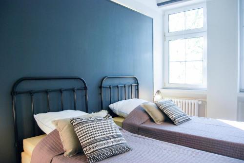 2 letti in una camera da letto con pareti blu di Alte Schule Gästehaus - The principal's rooms Appartment a Bitburg