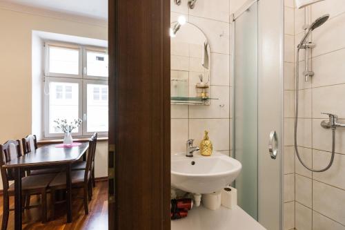 een badkamer met een wastafel, een tafel en een douche bij Vintage Senacka 5 Apartments in Krakau