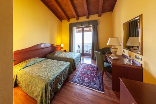 Habitación de hotel con 2 camas, escritorio y espejo. en Agriturismo Da Celestina en Arzignano