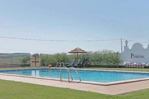 a swimming pool with chairs and an umbrella at Quinta da Pinheira Lezíria in Alpiarça