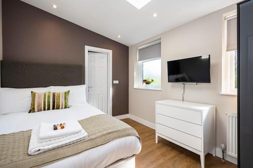 a bedroom with a white bed and a flat screen tv at South Woodford 2 Bed En-Suite House in London
