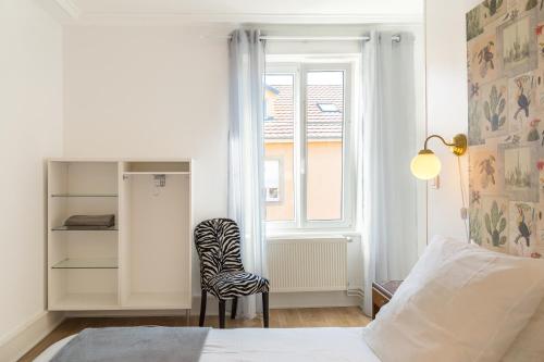 een slaapkamer met een bed, een stoel en een raam bij Le Victor Hugo in Colmar