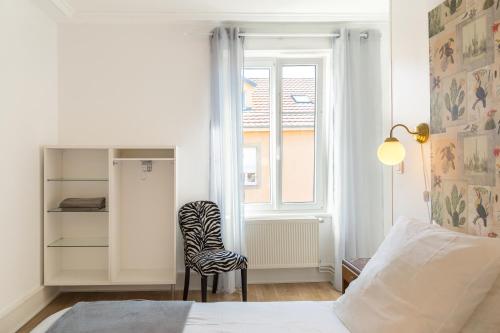 une chambre avec un lit, une chaise et une fenêtre dans l'établissement Le Victor Hugo, à Colmar