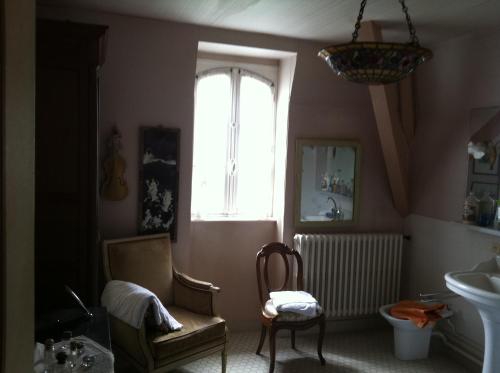 a bathroom with a window and a chair and a sink at Le Kino Panorama in Vic-sur-Cère