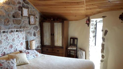 a bedroom with a bed and a stone wall at Cantinho da Coxixa in Monsanto