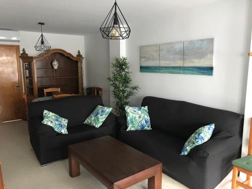 sala de estar con sofá negro y mesa en Playa San Miguel, en Cartaya