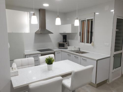 a white kitchen with a table and white chairs at Centre Apartment near Plaza de Toros in Alicante