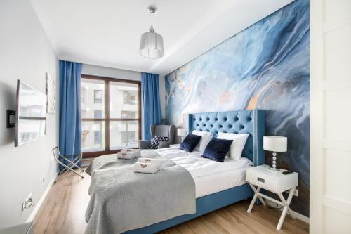 a blue and white bedroom with a large painting on the wall at Naviflat - West Side Apartment in Warsaw