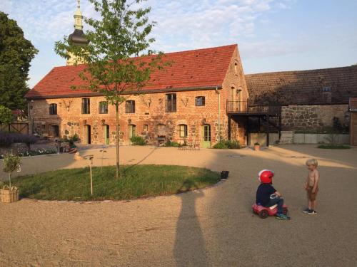 two children riding a toy car in front of a building at Ferienhaus am Schloss Meseberg in Meseberg