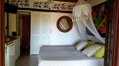 1 dormitorio con cama y espejo en la pared en Studio Bwa Banbou dans Villa Fleurs des Iles, en Le Vauclin