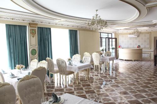 a dining room with white tables and white chairs at Firuze Hotel & Restaurant in Sheki