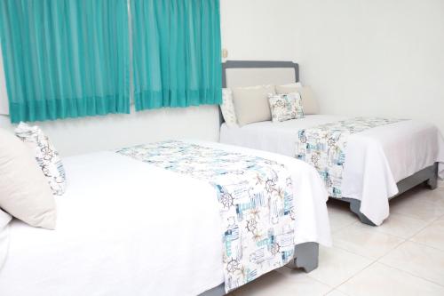 2 camas en una habitación con cortinas verdes en HOTEL VILLAS DEL MAR, en Pedernales