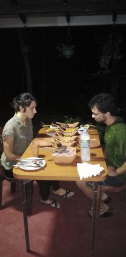 three people sitting at a table with food on it at Rainforest Holiday Inn in Deniyaya