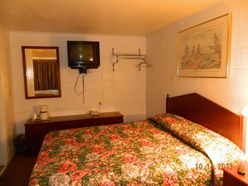 a bedroom with a bed and a tv on the wall at Relax Inn - Cottage Grove in Cottage Grove