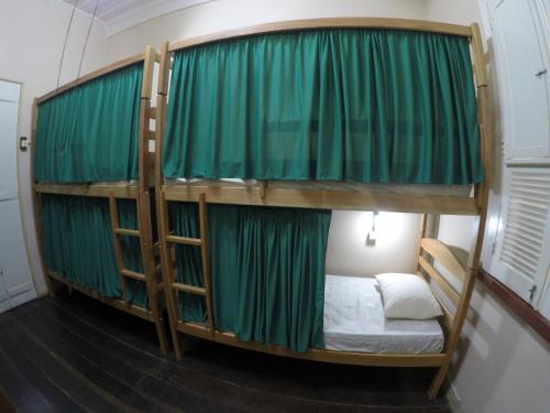 a room with two bunk beds with green curtains at Aldeia Hostel in Manaus