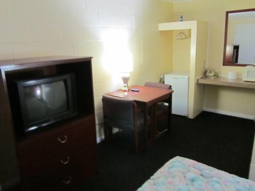 Habitación de hotel con TV y escritorio con lámpara. en Relax Inn - Cottage Grove, en Cottage Grove