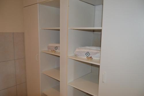 a walk in closet with white shelves and towels at Oppidam Self Catering Accommodation in Clanwilliam