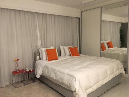 um quarto com uma grande cama branca com almofadas laranja em Loft Confortável e Moderno em São Paulo