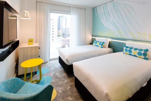 a hotel room with two beds and a chair at ibis Styles East Perth in Perth