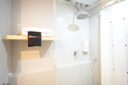 a bathroom with white walls and a shower at RedDoorz Apartment at Bogor Valley in Bogor