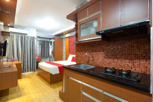 a room with a bed and a kitchen with a sink at RedDoorz Apartment at Bogor Valley in Bogor