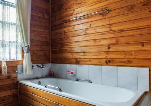 La salle de bains est pourvue d'une baignoire et de murs en bois. dans l'établissement Viewpoint Lodge & Safari Tours, à Hazyview